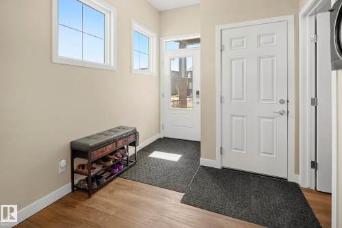 Entryway with wood-finish flooring, white trim, and a paneled door - 7135 Edgemont Way Nw, Edmonton, AB 