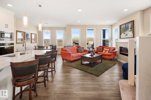 Open concept living area with wood-finish flooring, recessed lighting, and an electric fireplace - 7135 Edgemont Way Nw, Edmonton, AB 
