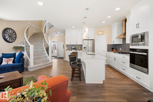 Bright open-concept living space with wood-finish flooring, a spiral staircase, and recessed lighting - 7135 Edgemont Way Nw, Edmonton, AB 