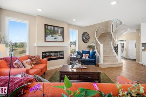 Recessed lighting, wood-finish flooring, and a modern fireplace with a white mantel - 7135 Edgemont Way Nw, Edmonton, AB 