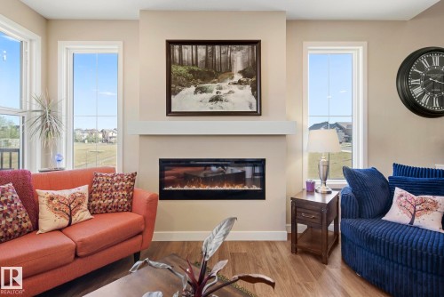 Built-in electric fireplace with a white mantel, accompanied by wood-finish flooring - 7135 Edgemont Way Nw, Edmonton, AB 