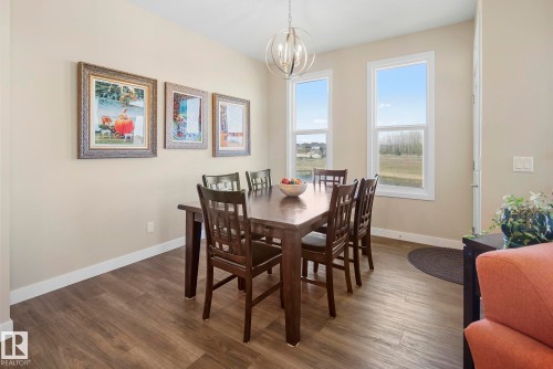 Wood-finish flooring, neutral wall tones, and an overhead spherical chandelier - 7135 Edgemont Way Nw, Edmonton, AB 
