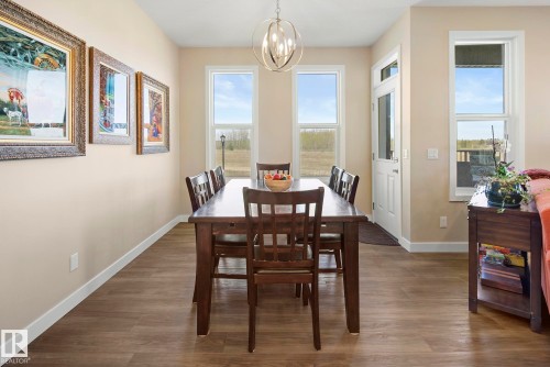 Wood-finish flooring, multiple large windows, neutral wall tones, and a contemporary light fixture - 7135 Edgemont Way Nw, Edmonton, AB 