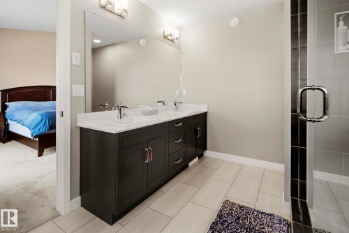 Dual vanity with white undermount sinks, chrome fixtures, and a large wall-mounted mirror - 7135 Edgemont Way Nw, Edmonton, AB 