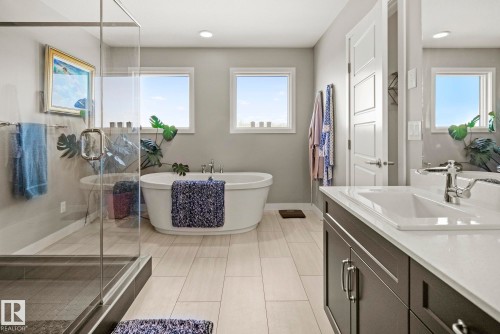 Freestanding soaking tub, glass-enclosed shower, dual vanity with undermount sinks, wood-finish flooring, and recessed lighting - 7135 Edgemont Way Nw, Edmonton, AB 