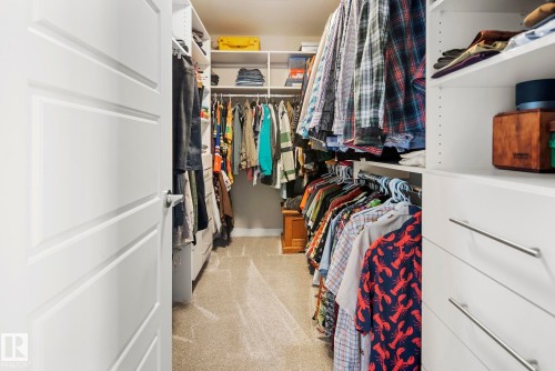 Recessed lighting illuminates custom closet organization with multiple shelving units, hanging rods, and integrated drawers with linear pulls - 7135 Edgemont Way Nw, Edmonton, AB 
