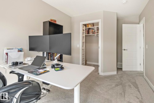 Carpet flooring, built-in shelving, and a modern five-panel interior door - 7135 Edgemont Way Nw, Edmonton, AB 