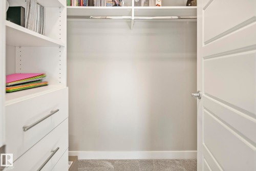 Built-in white shelving system featuring adjustable shelves and integrated drawers with linear pulls - 7135 Edgemont Way Nw, Edmonton, AB 