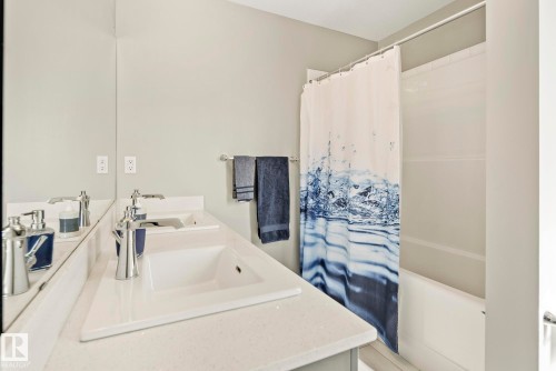 Dual vanity with integrated sinks, chrome faucets, and a full-width mirror - 7135 Edgemont Way Nw, Edmonton, AB 