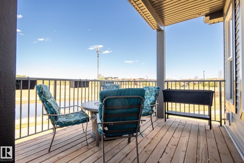 Covered deck featuring wood flooring, metal railings, and vinyl siding - 7135 Edgemont Way Nw, Edmonton, AB 