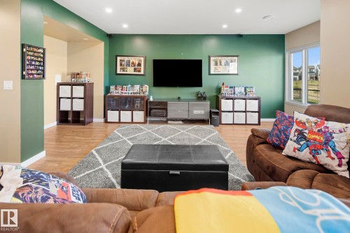 Recessed lighting, wood-finish flooring, accent wall, white window trim, and large windows - 7135 Edgemont Way Nw, Edmonton, AB 