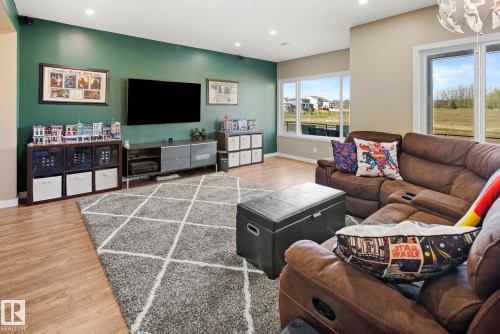 Spacious room featuring wood-finish flooring, recessed lighting, and large windows - 7135 Edgemont Way Nw, Edmonton, AB 