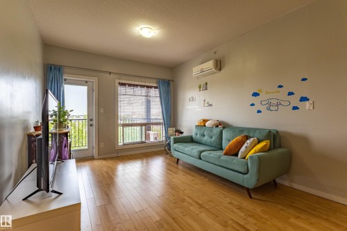 Open-concept living area featuring wood-finish flooring, light grey walls, and a recessed ceiling light - #407 9523 160 Av Nw, Edmonton, AB - Indoor Photo Showing Living Room