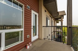 Private concrete balcony featuring a full-light entry door, large picture window, and black metal railings - 