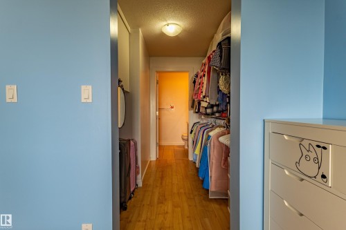 Hardwood-style flooring in a hallway leading to a closet with integrated shelving - #407 9523 160 Av Nw, Edmonton, AB - Indoor Photo Showing Other Room