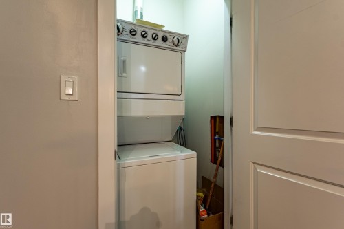 Dedicated laundry alcove featuring a stacked washer and dryer unit - #407 9523 160 Av Nw, Edmonton, AB - Indoor Photo Showing Laundry Room
