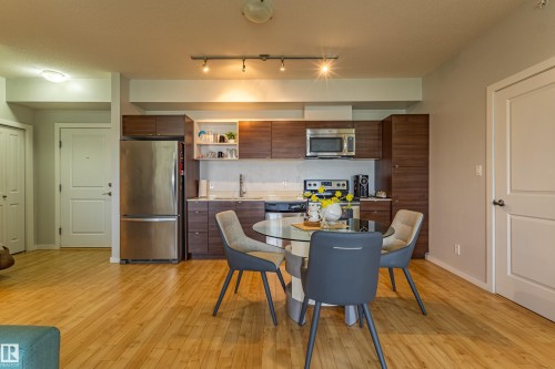 Open-concept kitchen and dining area featuring wood-finish flooring - #407 9523 160 Av Nw, Edmonton, AB - Indoor