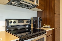 Stainless steel electric range with black cooktop, complemented by built-in wood-finish cabinetry, light-toned countertops, and a matching stainless steel microwave with ventilation - 