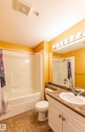 Bathroom featuring a white vanity with a countertop, an integrated sink, and a large mirror with vanity lighting - 
