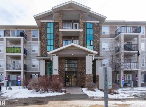 The property features a multi-story exterior with a stone facade accent, light-colored siding, and balconies with black railings - #1111 7339 South Terwillegar Dr Nw, Edmonton, AB - Outdoor With Facade
