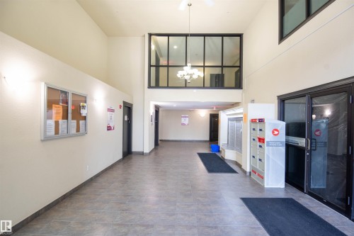 Spacious entry area featuring high ceilings, tiled flooring, and a second-story interior window with a chandelier - #1111 7339 South Terwillegar Dr Nw, Edmonton, AB - Indoor Photo Showing Other Room