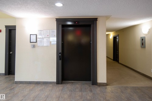 The property features an elevator with dark trim, set against light-colored walls - #1111 7339 South Terwillegar Dr Nw, Edmonton, AB - Indoor Photo Showing Other Room