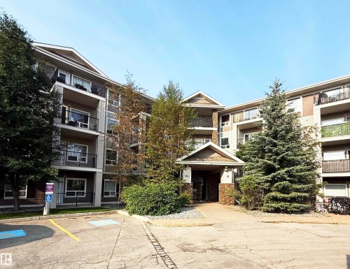 Multi-level building exterior featuring stone accents, covered entry, and individual balconies with black railings - #1111 7339 South Terwillegar Dr Nw, Edmonton, AB - Outdoor With Facade