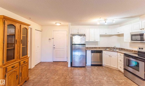 The kitchen features white cabinetry, stainless steel appliances, and a tiled floor - #1111 7339 South Terwillegar Dr Nw, Edmonton, AB - Indoor Photo Showing Kitchen With Stainless Steel Kitchen With Double Sink