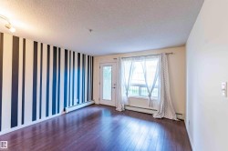 This space features dark hardwood flooring, a window with sheer curtains, and a door with a glass panel - 