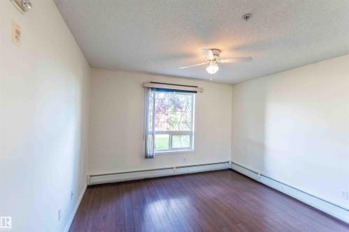 This room features dark wood flooring, a window with a view of greenery, and a ceiling fan with an integrated light fixture - #1111 7339 South Terwillegar Dr Nw, Edmonton, AB - Indoor Photo Showing Other Room