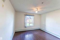 This room features dark wood flooring, a window with a view of greenery, and a ceiling fan with an integrated light fixture - 
