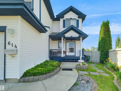 Two-story residence with white siding and dark trim, featuring a covered front porch, concrete pathway, and mature landscaping - 614 Silver Berry Road Nw, Edmonton, AB - Outdoor With Deck Patio Veranda