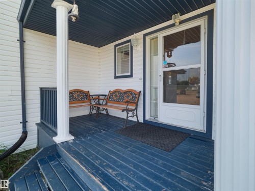Front porch with white siding, dark blue decking, and a white screen door - 614 Silver Berry Road Nw, Edmonton, AB - Outdoor With Deck Patio Veranda With Exterior