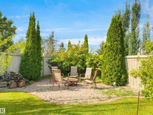 Landscaped yard featuring a gravel patio area with stone edging, privacy fencing, and mature trees - 614 Silver Berry Road Nw, Edmonton, AB - Outdoor With Backyard