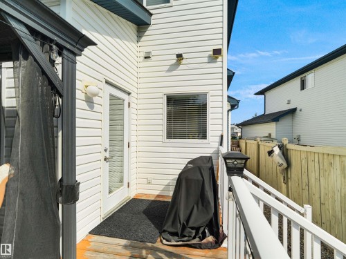 White vinyl siding exterior with a glass-paneled door, exterior wall lighting, and a deck with white railings - 614 Silver Berry Road Nw, Edmonton, AB - Outdoor With Exterior