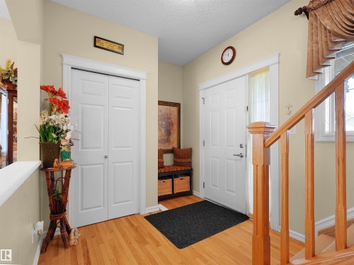 Wood-finish flooring, white paneled entry door with sidelight, white paneled bi-fold closet, and wood railing - 614 Silver Berry Road Nw, Edmonton, AB - Indoor Photo Showing Other Room