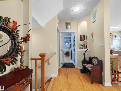 Hardwood flooring, wood staircase with railing, recessed wall niche, laundry area with built-in shelving, and a built-in kitchen island with a wood base - 614 Silver Berry Road Nw, Edmonton, AB - Indoor Photo Showing Other Room