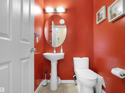 Pedestal sink, wall-mounted oval mirror, and overhead vanity lighting - 614 Silver Berry Road Nw, Edmonton, AB - Indoor Photo Showing Bathroom