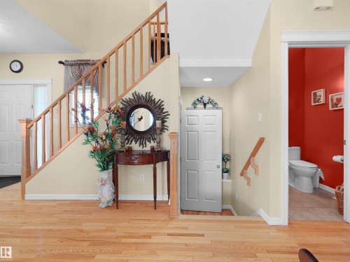 Hardwood flooring, natural wood staircase with spindles, recessed lighting, and a white interior door - 614 Silver Berry Road Nw, Edmonton, AB - Indoor Photo Showing Other Room
