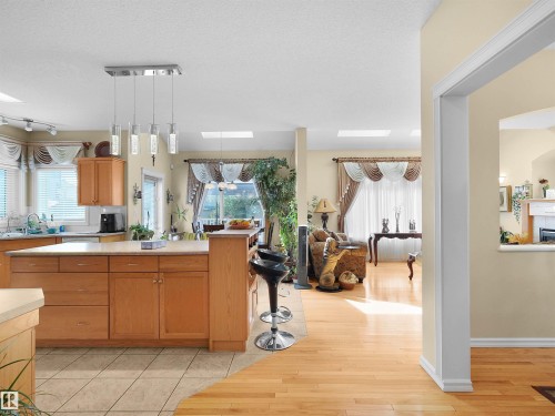 Kitchen island with light wood cabinetry and light-toned countertop, featuring a modern pendant light fixture - 614 Silver Berry Road Nw, Edmonton, AB - Indoor Photo Showing Other Room