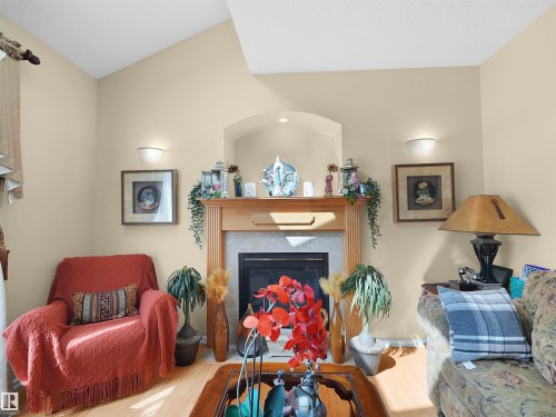 Vaulted ceiling, fireplace with wood-finish mantel, tile surround, recessed lighting, and wall sconces - 614 Silver Berry Road Nw, Edmonton, AB - Indoor Photo Showing Living Room With Fireplace