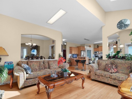 Wood-finish flooring, vaulted ceiling, arched wall openings, recessed ceiling lighting, and a built-in kitchen bar with seating - 614 Silver Berry Road Nw, Edmonton, AB - Indoor Photo Showing Living Room