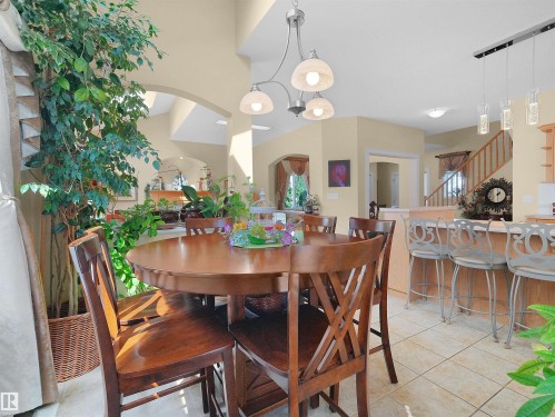 Spacious dining area with a round wood-finish table, recessed lighting, and a breakfast bar with seating - 614 Silver Berry Road Nw, Edmonton, AB - Indoor Photo Showing Dining Room