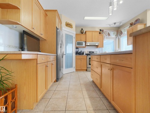 Kitchen featuring light wood-finish cabinetry, light-toned countertop, tile flooring, and stainless steel appliances - 614 Silver Berry Road Nw, Edmonton, AB - Indoor Photo Showing Kitchen