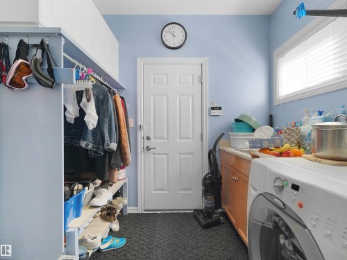Built-in wood-finish cabinetry with light countertop, white paneled door, and laundry appliances - 614 Silver Berry Road Nw, Edmonton, AB - Indoor Photo Showing Laundry Room