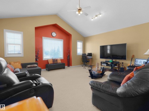 Vaulted ceiling, ceiling fan with integrated lighting, recessed wall feature, multiple windows, and neutral carpet flooring - 614 Silver Berry Road Nw, Edmonton, AB - Indoor Photo Showing Living Room