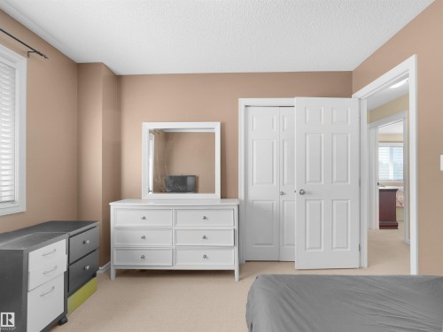 Neutral paint palette, textured ceiling, window with white blinds, and a built-in closet with panel doors - 614 Silver Berry Road Nw, Edmonton, AB - Indoor Photo Showing Bedroom