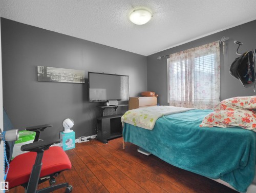 Warm wood-finish flooring, neutral painted walls, and a window with blinds provide natural light - 614 Silver Berry Road Nw, Edmonton, AB - Indoor Photo Showing Bedroom