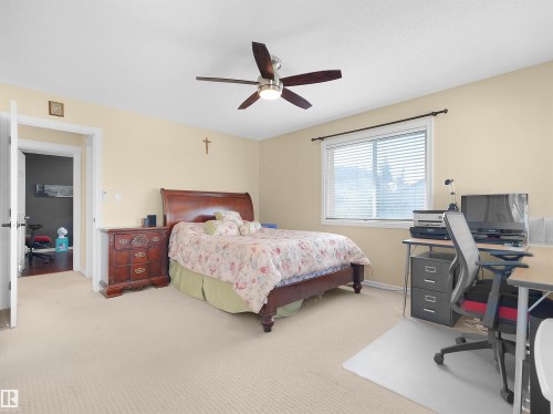 Neutral-toned carpeting, a window with horizontal blinds, and a ceiling fan with integrated lighting - 614 Silver Berry Road Nw, Edmonton, AB - Indoor Photo Showing Bedroom