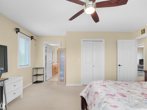Ceiling fan with integrated lighting, window with blinds, bi-fold closet doors, and light-colored wall paint - 614 Silver Berry Road Nw, Edmonton, AB - Indoor Photo Showing Bedroom